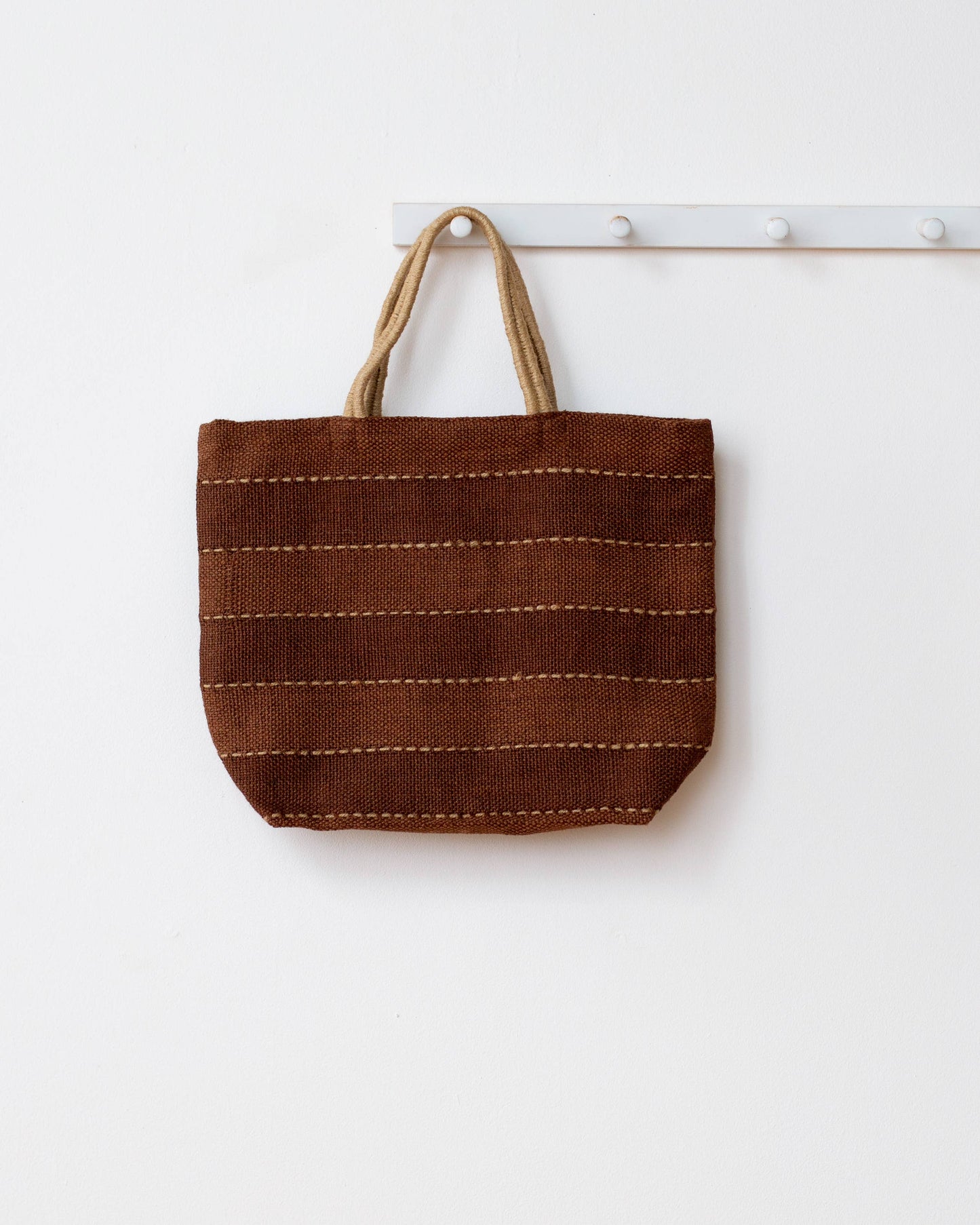 Brown woven tote bag with beige handles on a white background