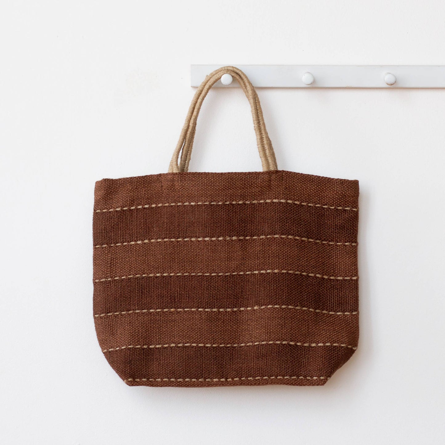 Brown woven tote bag with a handle on a white background