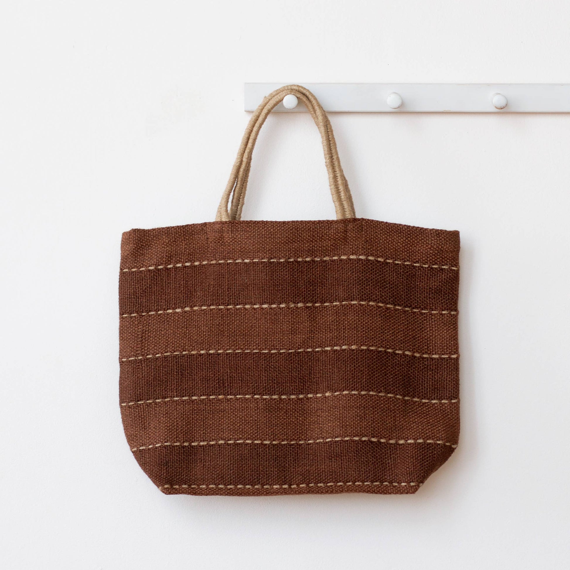 Brown woven tote bag with a handle on a white background