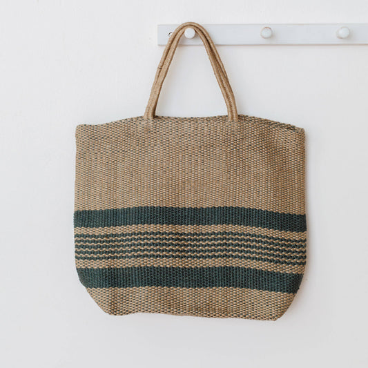 Woven tote bag with striped pattern hanging on a white wall