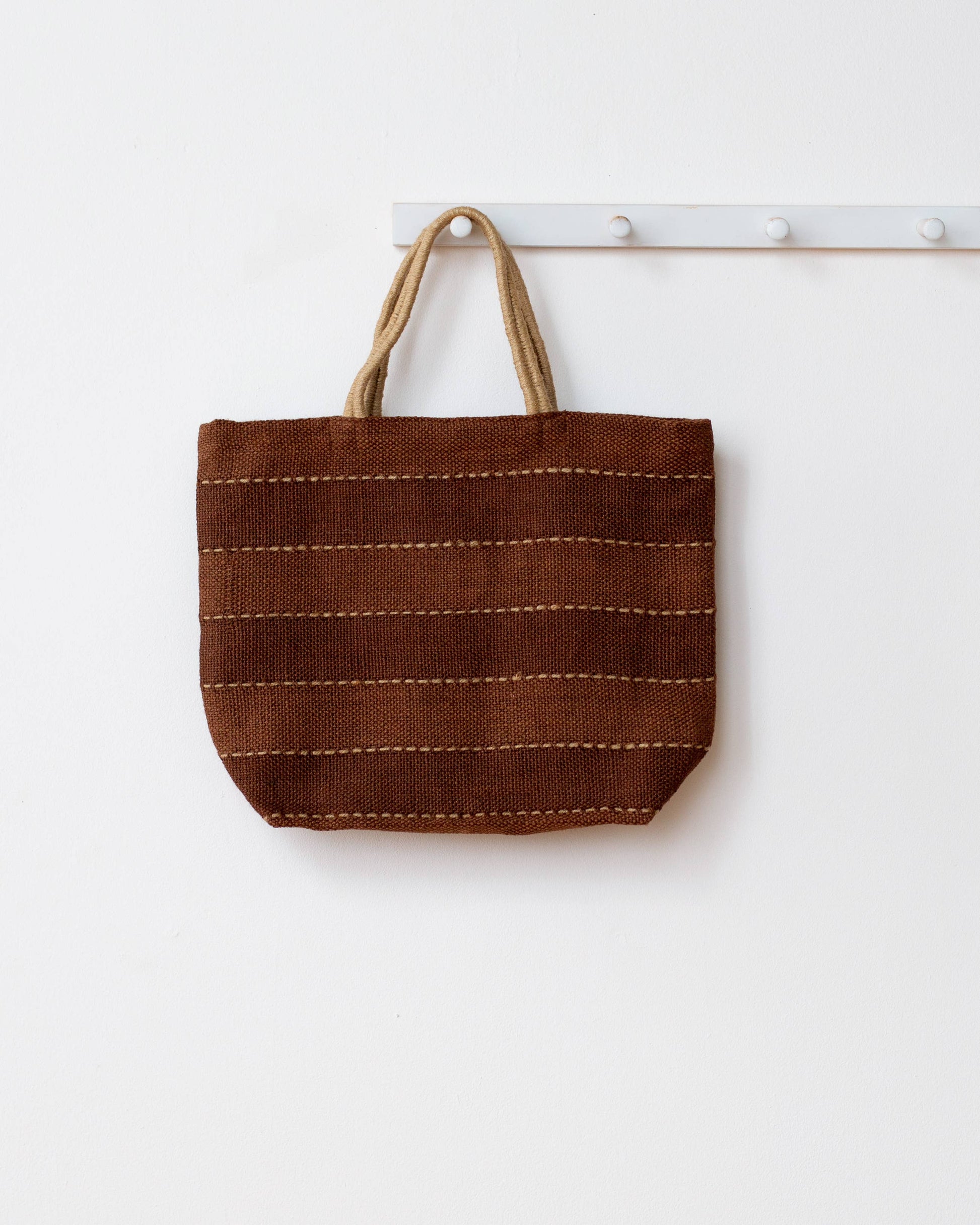 Brown woven tote bag with beige handles on a white background