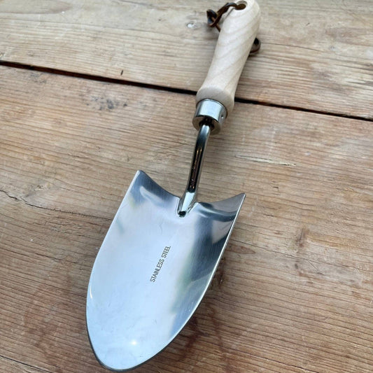 Gardening trowel with wooden handle on a wooden surface