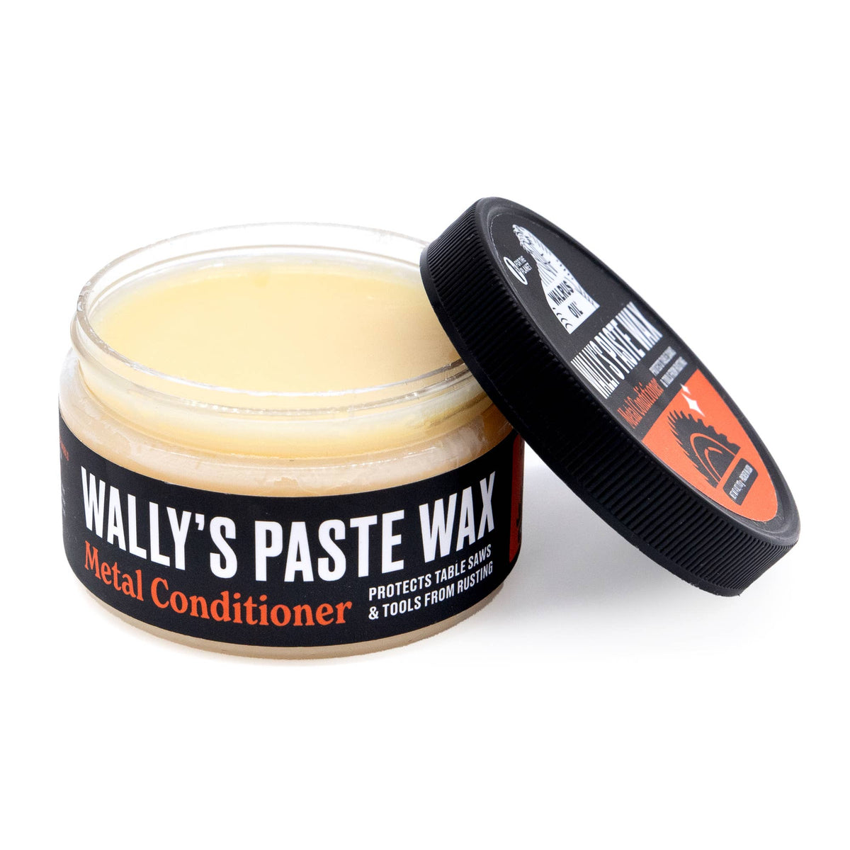 An open jar of Wally's Paste Wax Metal Conditioner showing the pale yellow wax inside, with its black lid leaning against it on a white background.
