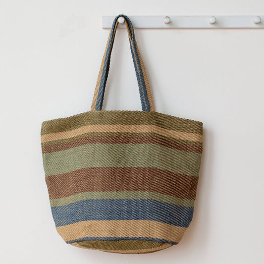 Striped tote bag hanging on a white wall with a coat rack.